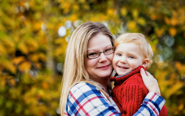 Outdoor portrait of a mother holding young son close, in a park area in autumn; Edmonton, Alberta, Canada