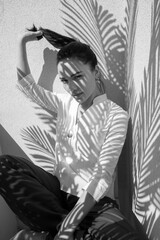 black and white photo of a brunette woman sitting in the shade of a plant