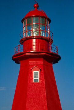 Brightly painted red lighthouse against a blue sky; Gaspe Peninsula, La Martre, Quebec, Canada