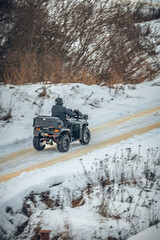 a rider on an ATV rides on a winter road