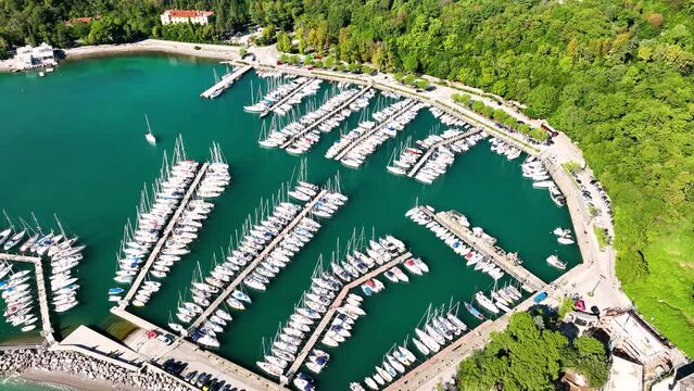 MONFALCONE, ITALY - APRIL, 2023: Sailing yacht moored off the coast Adriatic sea in Italy at sunny day. Drone aerial view, cinematic frame. Romantic atmosphere. Calm and pacifying scene.