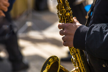 close-up of the hands of a street musician playing the saxophone
