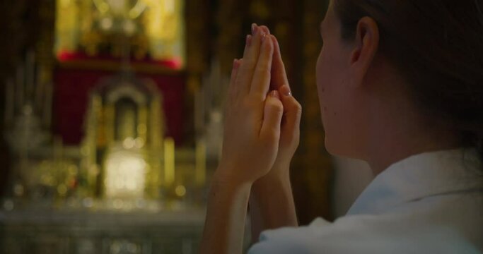 Christian woman folded hands in prayer in church.