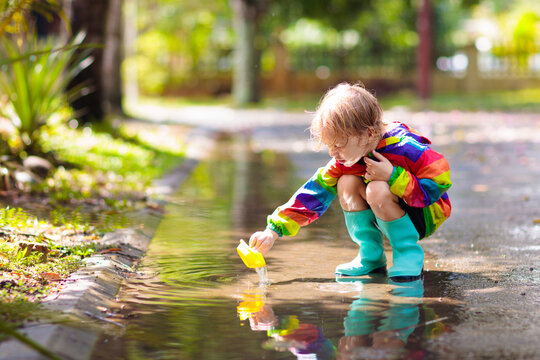 Kids in puddle in autumn rain. Waterproof wear