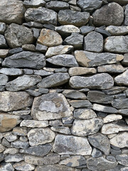 The wall is made of large and small gray stones, side view, texture