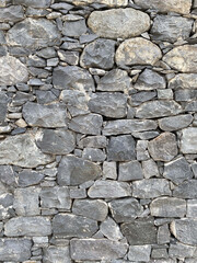 The wall is made of large and small gray stones, side view, texture