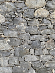 The wall is made of large and small gray stones, side view, texture