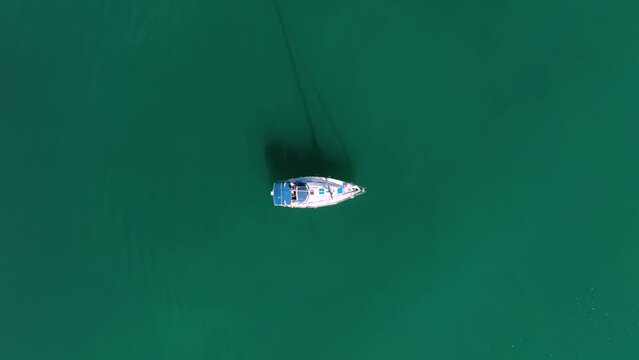 MONFALCONE, ITALY - APRIL, 2023: Sailing yacht moored off the coast Adriatic sea in Italy at sunny day. Drone aerial view, cinematic frame. Romantic atmosphere. Calm and pacifying scene.