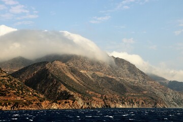 clouds descending from the mountains to the sea in the morning on Karpathos island in Greece 