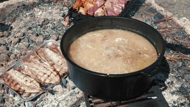Cauldron with kulish prepared on fire. Picnic time. Barbecue meat frying on fire