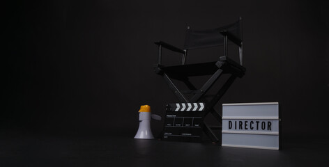 Black director chair and clapper board and light box and megaphone on black background.