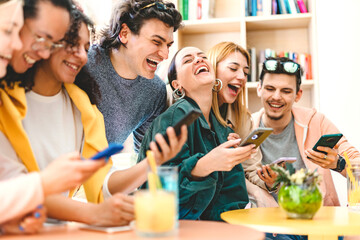 Group of happy students having fun using mobile phone and sharing social content- Young millenial friends watching smartphone at university classroom-Life style Internet Technology concept 