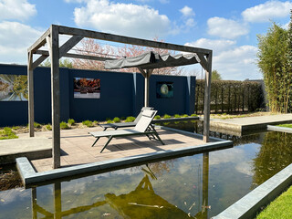 Large terrace and sun chairs by the water. Appeltern, Netherlands, April 09, 2023: The garden...