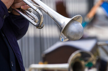 close-up of the hands of a street musician holding a gold-colored pump-action trumpet