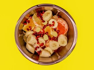 fruit cut for salad, orange, grapefruit, lemon, pomegranate. Photo from above, yellow background