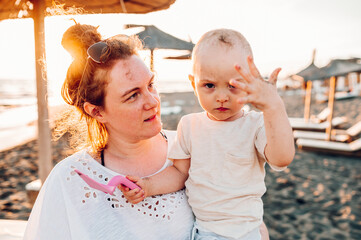 Portrait of a little boy and his mother on the beach during the golden hour.