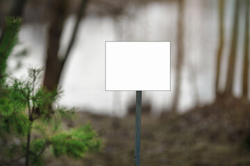 Information or advertisement white blank sign board mounted in forest or urban park outdoor.