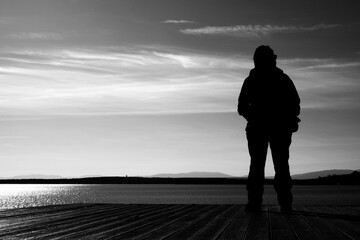 A woman posing on a pier by a lake meditating while looking at the world around her