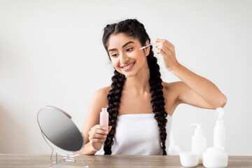 Skincare Cosmetics. Beautiful Indian Woman Applying Moisturizing Face Serum With Dropper