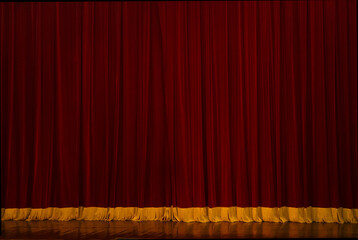 Theatrical curtain is red heavy velvet with gold fringe underneath.