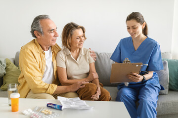 Nurse during home visit with senior couple, doctor holding clipboard in conversation with old man...