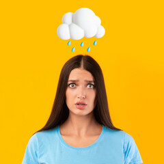 Sad young european female with abstract cloud and rain sign above head isolated on yellow studio background