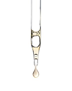 Cosmetic serum pipette with a yellow drop oil or aha asids close up on white isolated background