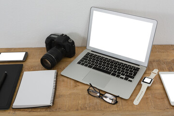 Laptop, wristwatch, notepad, camera and mobile phone on wooden table
