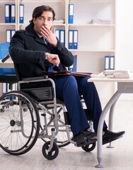 Young male employee in wheelchair working in the office