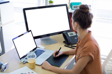 Side view of businesswoman working over graphic tablet at desk