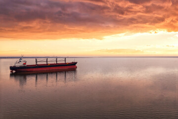 Cargo ship in the open sea at the beautiful sunset. Aerial top view.Shipping. Grain export