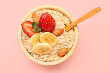 Bowl with tasty oatmeal, almonds, bananas and strawberries on pink background - Powered by Adobe