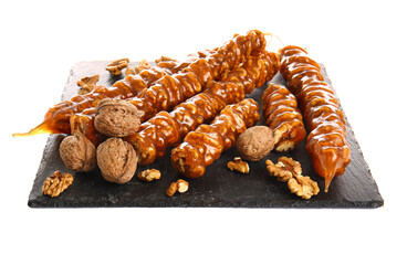 Slate board with tasty churchkhela and walnuts on white background
