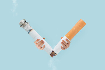 V-shaped victory symbol made with broken cigarette held by man's hands on isolated pastel blue background. Minimal creative abstract surrealist poster of  World no tobacco day. Quit smoking card.