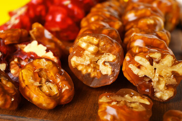 Delicious churchkhela with walnuts on wooden board, closeup