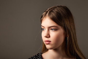 Close up portrait of pretty jewish teenage girl with long hair and blue eyes, looking away. Face of serious cute jew teen lady closeup, studio shot. Youth positive emotion concept. Copy ad text space