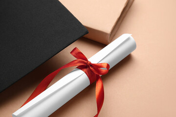 Diploma with red ribbon, graduation hat and book on brown background