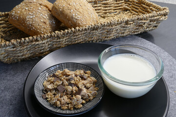 Müsli in einer Schale und Brötchen im Korb