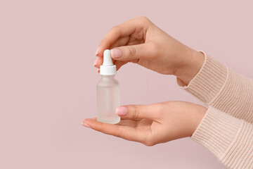 Female hands with bottle of healthy cuticle oil on color background, closeup