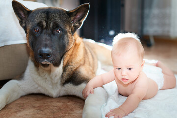 A little boy and a big dog are lying on the floor in a room, friendship and interaction of people and animals from an early age, family and relationships.