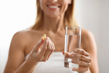 Smiling Middle Aged Woman Holding Vitamin Capsule And Glass Of Water