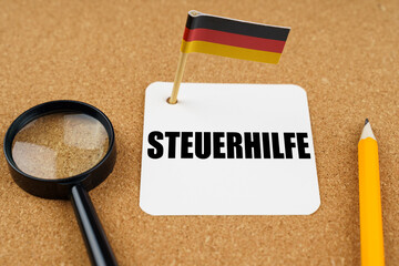 On the table is the flag of Germany, a pencil and a sheet of paper with the inscription - TAX Help