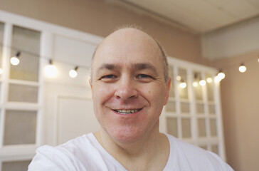 Smiling male blogger taking a selfie or video call from his apartment