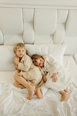 Brother and sister lying on the bed in bathrobes after a shower