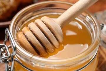 Jar of sweet honey with dipper on table, closeup