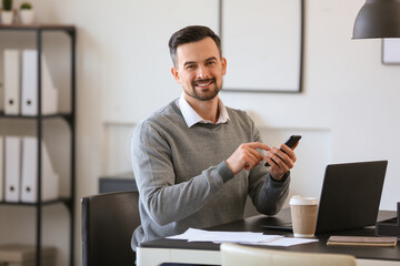 Handsome businessman working with mobile phone at table in office