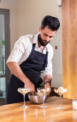 Homemade tiramisu in glass jars cooking process. Traditional unbaked italian dessert. Coffee and mascarpone cream cake