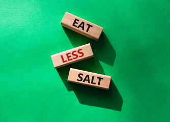 Eat less salt symbol. Concept word Eat less salt on wooden blocks. Beautiful green background....
