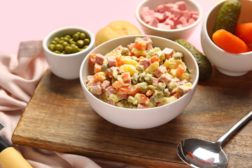 Bowl of tasty Olivier salad on pink background