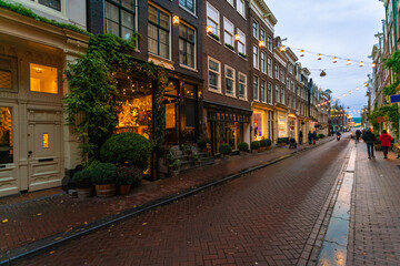 Fototapeta na wymiar Narrow street with shops at the old town by sunset in Amsterdam, the netherlands